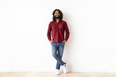 Neşeli, mutlu, şık Hintli adam ellerini pantolonunun cebine sokup beyaz duvar arkasında poz veriyor kameraya gülümsüyor, yeni bir daire alıyor, fotokopi çekiyor. Milenyum Yaşamı