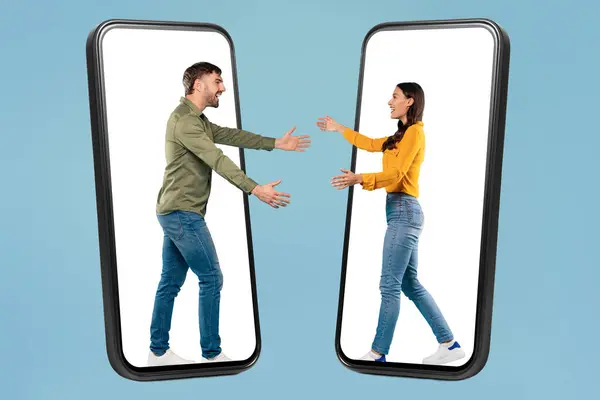 年轻男女给予虚拟拥抱 创造性地放置在两个蓝色背景的智能手机框架内 全长镜头 — 图库照片