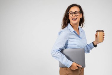 Neşeli Avrupalı bin yıllık iş kadını profesyonel bir bilgisayar ve kahve servisi, fotokopi alanına bak, gri stüdyo arka planında izole edilmiş. İş, iş molası, reklam ve teklif