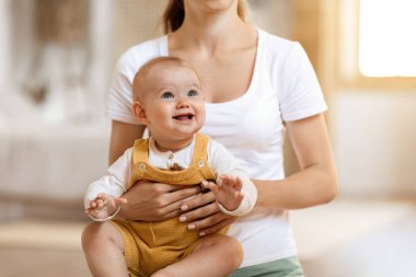 Gülümseyen sarışın bebek anne kollarında oturup gülüyor. Tanınmayan bir anne ve tatlı bir çocuk evde birbirlerine sarılıyorlar, mekanı kopyalıyorlar. Çocuk bakımı kavramı