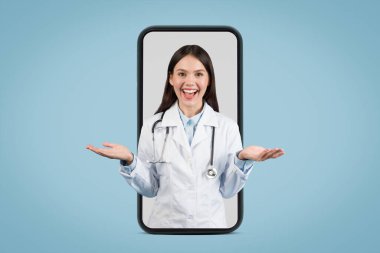 Tıbbi üniformalı genç Avrupalı bayan doktor jest yaparak karşılıyor, büyük bir telefon ekranında gülümsüyor, mavi arka planda online danışmanlık somutlaştırıyor.