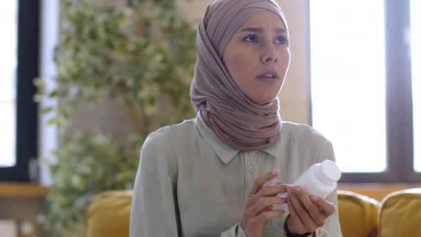 食品补充剂概念 年轻漂亮的穆斯林女士头戴头巾 头戴头巾 阅读罐子上的说明 打开瓶子 跟踪镜头 慢动作 — 图库视频影像