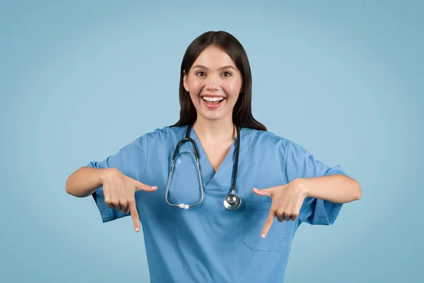 Молода Європейська Леді Медсестра Блакитній Медичній Формі Вказує Вниз Посміхається — стокове фото