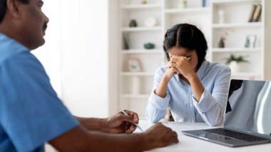 Klinikte doktorla görüşürken üzgün kadın hasta ağlıyor, Hintli kadın kötü tanı koyduktan sonra umutsuzluğa kapılıyor, erkek terapist tedavinin detaylarını paylaşıyor, seçici odaklanma