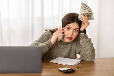 Masasında dizüstü bilgisayarla oturan endişeli genç bir kadın tüccar, elinde nakit para tutuyordu. İş kadını, iş arkadaşlarıyla telefonda konuştuğu mali haberlerden hayal kırıklığına uğradı.
