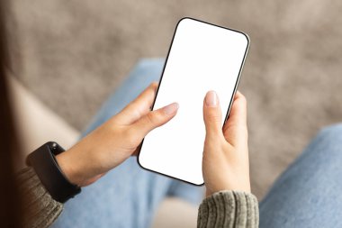 Beyaz ekranlı telefonu kullanan tanınmayan bir kadın. Bayan eller akıllı telefonu fotokopi alanı ile tutuyor, mobil uygulama kullanıyor, kaydırıyor, arkadaşlarla sohbet ediyor, üst görünüm