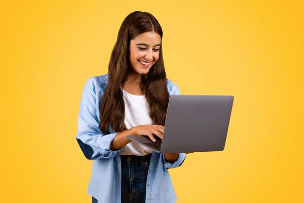 快乐漂亮的欧洲少女在电脑上打字 孤立在黄色的背景上 生活方式和工作 远程学习和家庭作业 教育和在线课程 — 图库照片