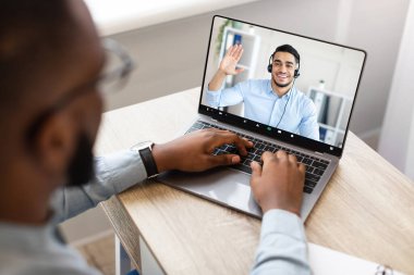Siyahi İşadamı 'nın Orta Doğulu İş Ortağıyla Modern Ofis' teki İş Yeri 'nde Dizüstü bilgisayarla İş Görüşmesi Yaparken Yüksek Açısı Bakış Açısı. Bilgisayara Seçici Odaklanma