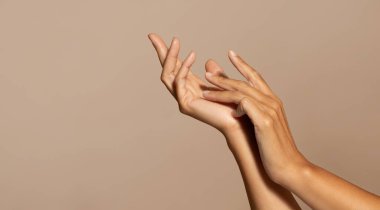 Beyaz tenli yaşlı bir kadının elleri cilt bakımından hoşlanır, bej renkli stüdyo arka planında izole edilmiş, kapalı, boş alan. Güzellik bakımı, spa prosedürleri, nemlendirme, reklam ve teklif, kozmetik satışı