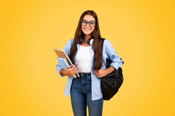 积极的书呆子少年白种人女学生戴眼镜 背着书包 享受学习 隔离在黄色的工作室背景 教育中的学生生活方式 — 图库照片