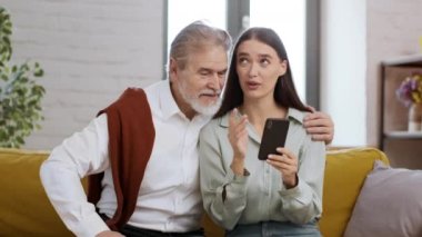 Aile iletişimi ve modern teknolojiler. Tasasız genç bayan büyükbabasıyla vakit geçiriyor, akıllı telefondan haber okuyor ve onları tartışıyor.