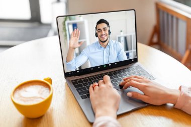 Laptop kullanan tanınmayan genç bir kadın, dost canlısı Orta Doğulu iş danışmanıyla görüntülü görüşme yapıyor, internet kafede oturuyor, ekin, fotokopi çekiyor.