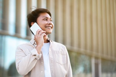 Genç Asyalı girişimci şehir merkezinde yürürken telefonla konuşuyor. Mutlu Milenyum Çinli işadamlarının yemek molasında reklam için fotokopi alanlarına bakmaları gerekiyor.
