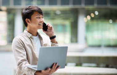 İş, girişimcilik, başlangıç konsepti. Elinde dizüstü bilgisayarı olan, telefonda konuşan, reklam için fotokopi çeken Asyalı bir girişimci.