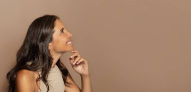 Doğal makyajlı dalgın Avrupalı yaşlı kadın, cilt bakımından hoşlanıyor, boş alana bakıyor, bej renkli stüdyo arka planında izole edilmiş. Güzellik bakımı, spa prosedürleri, reklam ve teklif