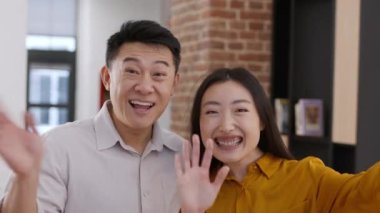 Aile blogu. Mutlu Asyalı evli erkek ve kadın akıllı telefondan sosyal medyaya video mesajı kaydediyor, birlikte ev içinde duruyorlar, kamera pov portresi
