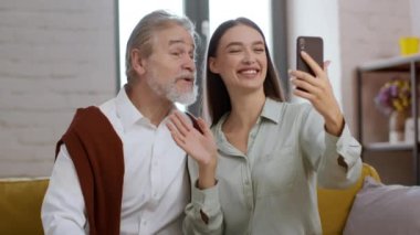 Modern iletişim teknolojileri. Genç, mutlu bir kadın büyükbabasına video sohbet uygulaması gösteriyor. Yaşayan akrabalarına sesleniyor. İzleme çekimi, yavaş çekim.