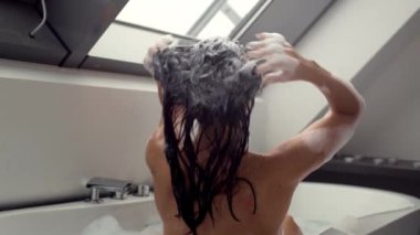 Çarpıcı 4K video görüntüleri banyoda güzel bir kadının saçını titizlikle köpüklü şampuanla ağır çekimde yıkadığını gösteriyor. Sahne, kişisel bakım ve güzellik rutinlerinin samimi anlarını sergiliyor.