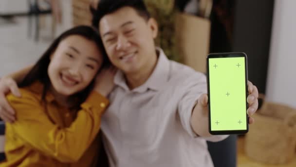 Migliore App Famiglia Sfocato Coppia Asiatica Incollaggio Casa Mostrando Smartphone Filmato Stock