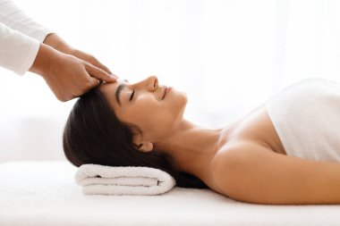 Zarif bir şekilde atanmış bir sağlık merkezinde, profesyonel bir masör, havluya sarılı genç ve güzel bir Hintli kadının kaşlarını yatıştırır, rahatlamasını, yan bakışını arttırır.