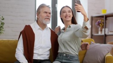Mutlu anılar yakalıyor. Genç mutlu kadın dedesini ziyarete geliyor. Akıllı telefonda selfie çekiyor, kameraya sarılıyor ve gülümsüyor.