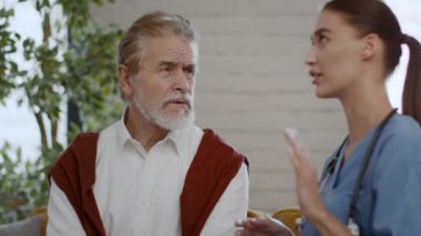 Tıbbi danışmanlık. Genç, profesyonel hemşire kıdemli bir hastayla konuşuyor, ona teşhis koyuyor ve sakinleştiriyor.