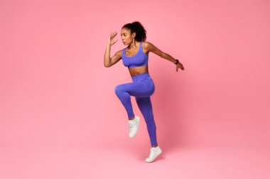 Pembe Stüdyo Arkaplanı, Tam Uzunluk, Yan Görüş Antrenmanı sırasında spor giyinen Afrikalı Afro-Amerikan bayan atlama egzersizi. Spor Motivasyonu ve Spor Konsepti