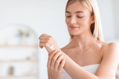 Beyaz havluya sarılı çekici sarışın kadın modern banyodaki ellerine ve kollarına nemlendirici sürüyor kuru cilt tedavisi için nemlendirici kullanıyor. Sağlıklı cilt rutini, sağlık ve güzellik.