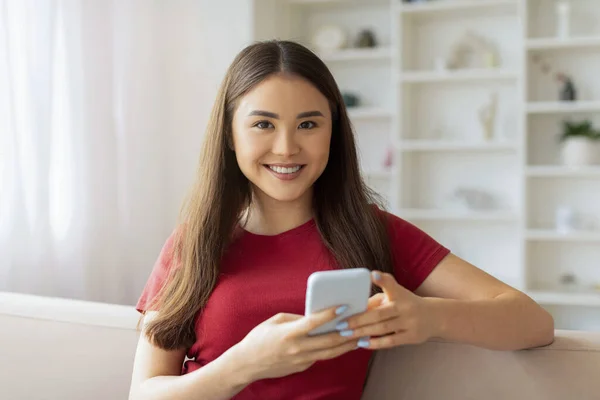 Schöne Lächelnde Asiatin Mit Smartphone Den Händen Die Hause Auf — Stockfoto