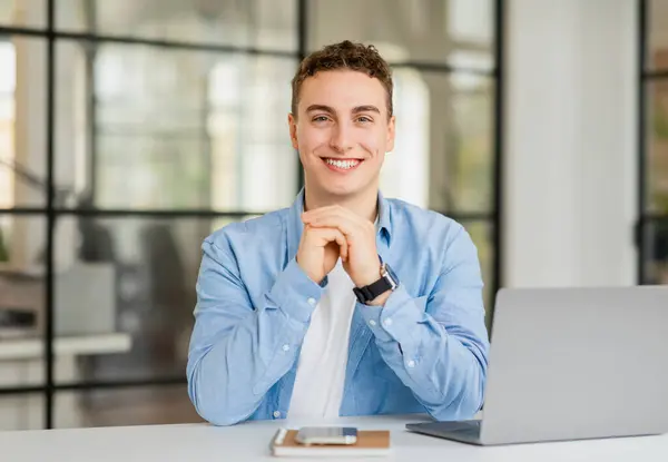 Positive handsome young european man manager in casual with laptop at table in coworking office. Project, planning startup, work, business in modern workplace, job lifestyle