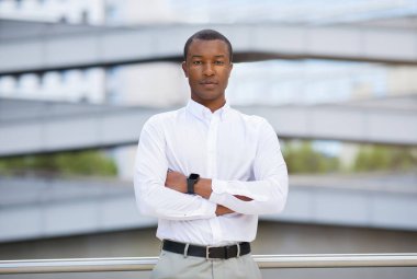 Tişörtlü yakışıklı siyahi işadamı dışarıda kolları bağlı duruyor, milenyum Afrikalı Amerikalı erkek girişimci kameraya bakıyor, modern iş merkezinin yakınında poz veriyor, uzay kopyası yapıyor.