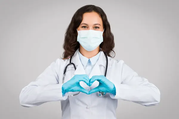 手袋をした手で心臓形状を形成し 医療における愛情と思いやりを象徴する女性の医師を世話する — ストック写真