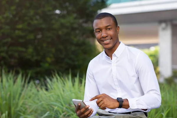 Uśmiechnięty Afro Amerykański Biznesmen Smartfonem Dłoni Siedzi Ławce Zewnątrz Przystojny — Zdjęcie stockowe