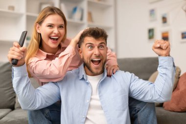 Zaferin sevinci. Duygusal Neşeli Genç Çift Yumruk Sallıyor Televizyon İzliyor, Favori Spor Takımının Evde Oturan Zaferini Kutluyor. Aile Hafta sonu Tatili, TV Programı