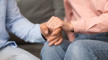 Evlilik, aşk ve birlik. Genç çiftlerin elleri nazikçe birbirine sarılır, kadın içeride yüzük takar. Sıkıca sarılmış ellerin samimi jesti. Ortaklar arasındaki bağ ve sevgi. Panorama