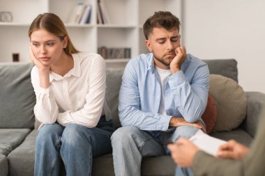 Genç evli çift psikoterapist ofisindeki koltukta oturmuş terapistin rehberliğiyle ilişki sorunlarıyla yüzleşiyorlar. Evlilik yardımı kavramı. Seçici odak