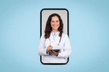 Sağlık hizmetleri. Üniformalı, steteskop ve tabletli, kameraya gülümseyen, cep telefonu ekranından dışarı bakan dost canlısı genç bayan doktor.