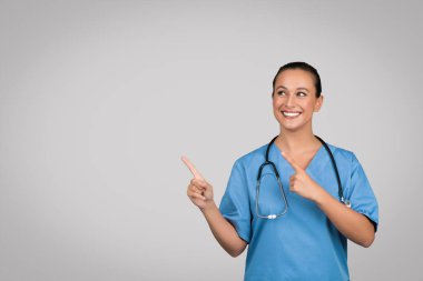 Avrupalı doktor, gri arka planda izole edilmiş, reklam için uygun bir yeri işaret ettiği için memnunum. Tıbbi yardım, sağlık hizmeti tavsiyesi, teklif, ilgi