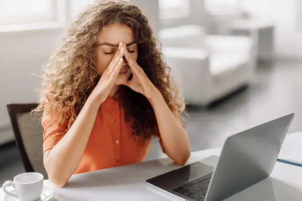 Kobieta Kręconymi Włosami Odczuwa Stres Pocierając Nos Zamkniętymi Oczami Siedząc — Zdjęcie stockowe
