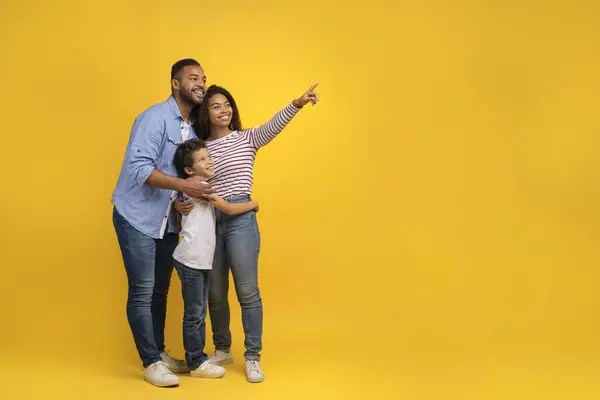 コピースペース 若い黒人の両親と長男の息子の幸せなアフリカ系アメリカ人の家族 あなたのテキストのための自由な場所を示し 黄色いスタジオの背景に一緒にポジショニング — ストック写真