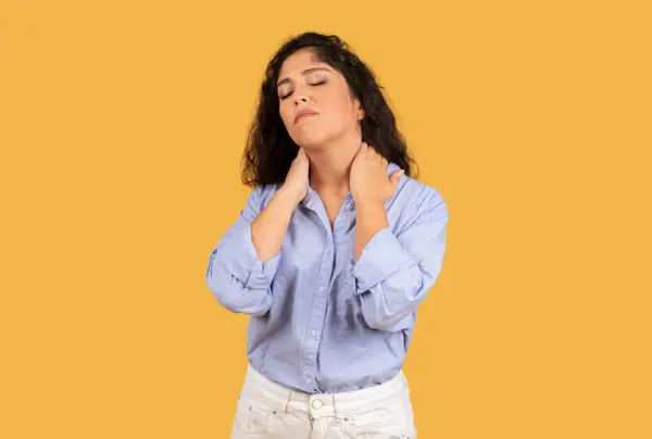 垂头丧气的年轻女子 用手按摩脖子 黄底隔离 压力或疼痛 过度工作和保健问题 精疲力竭 — 图库照片