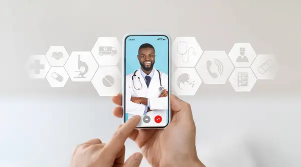Smiling black doctor consulting male patient remotely by video call on smartphone. Unrecognizable man getting online consultation via web conference with black therapist, creative collage, closeup