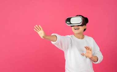 Heyecanlı genç Asyalı kadın VR gözlük kullanıyor, fotokopi uzayında görünmez bir şeye dokunuyor, milenyum kadını parlak pembe stüdyo arka planında sanal gerçeklik macerası yaşıyor, panorama