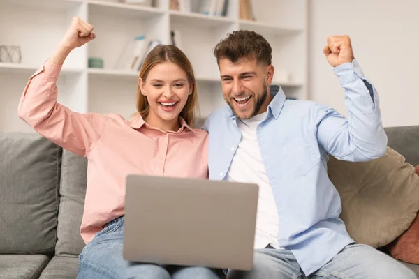 Genç Eşler Zaferlerini Oturma Odasında Dizüstü Bilgisayarlarında Kutluyorlar Erkek Kadın — Stok fotoğraf