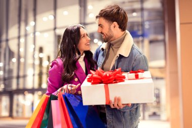 Alışveriş torbaları ve hediye paketleriyle gülümseyen genç Avrupalı çift, kış tatili alışveriş çılgınlığının tadını çıkarıyor. Geceleri, Noel 'i, yıldönümünü ya da sevgililer gününü kutluyorlar.