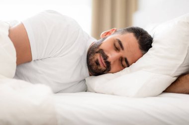 Bin yıllık barışçıl bir adam beyaz battaniyeyle örtülmüş bir şekilde derin bir uykuya dalıp, yatak odasında kestirirken yastığı kucaklıyor. Sağlıklı dinlenme ve sağlıklı uyku zamanı kavramı