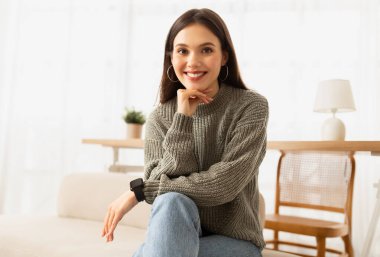 Oturma odasındaki kanepede oturan mutlu, huzurlu genç kadın, dinleniyor, işten izin alıyor, mekanı kopyalıyor. Güzel esmer bayan hafta sonu sabahı dinleniyor.