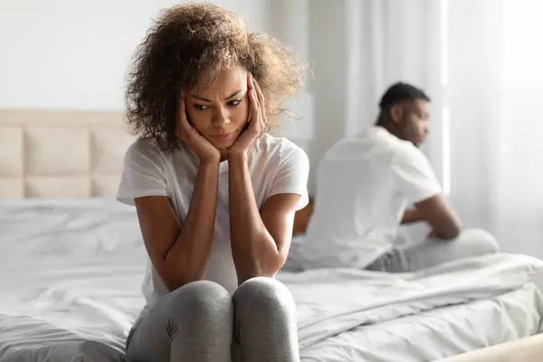 Marital Crisis. Unhappy Black Young Couple Sitting On Different Sides Of Bed, Sulking After Quarrel At Home Bedroom Interior, Suffering From Indifference, Disagreement And Relationship Issues