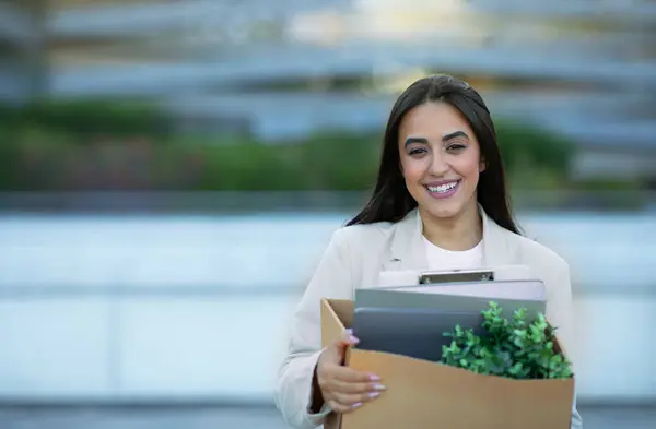 快乐的阿拉伯女商人带着一盒箱东西站在现代写字楼附近的城市地区 微笑着对着相机 快乐地开始新的工作 就业机会 复制空间 — 图库照片