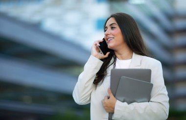 Başarılı İş İletişimi. İş görüşmesi için cep telefonu kullanan genç Arap iş kadını şehir merkezindeki şirket binasının önünde dikiliyor. Her zaman görüşüyoruz. Boş alan